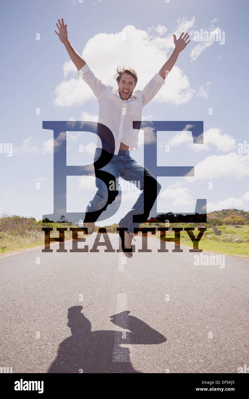 Imagen compuesta de apuesto hombre casual saltando sobre un camino sonriendo a la cámara Foto de stock