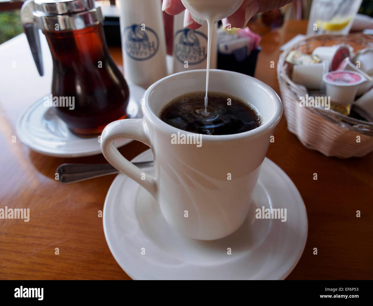 Agregar creamer para una taza de café en un café en el desayuno Foto de stock