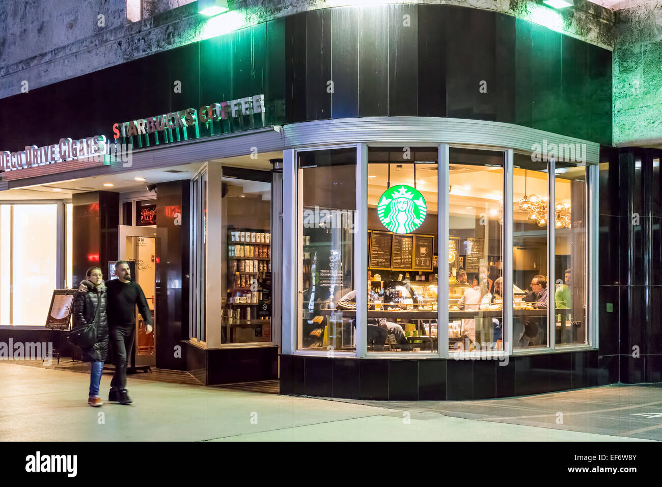 Noche en Lincoln Road Mall Starbucks Coffee Shop con personas sentadas bebiendo café dentro y un