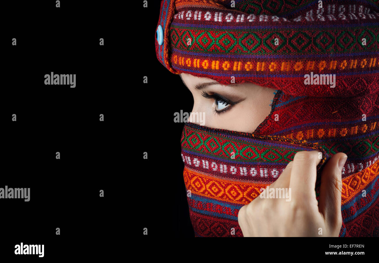 Mujer Oriental en el turbante que cubre su rostro sobre fondo negro Foto de stock
