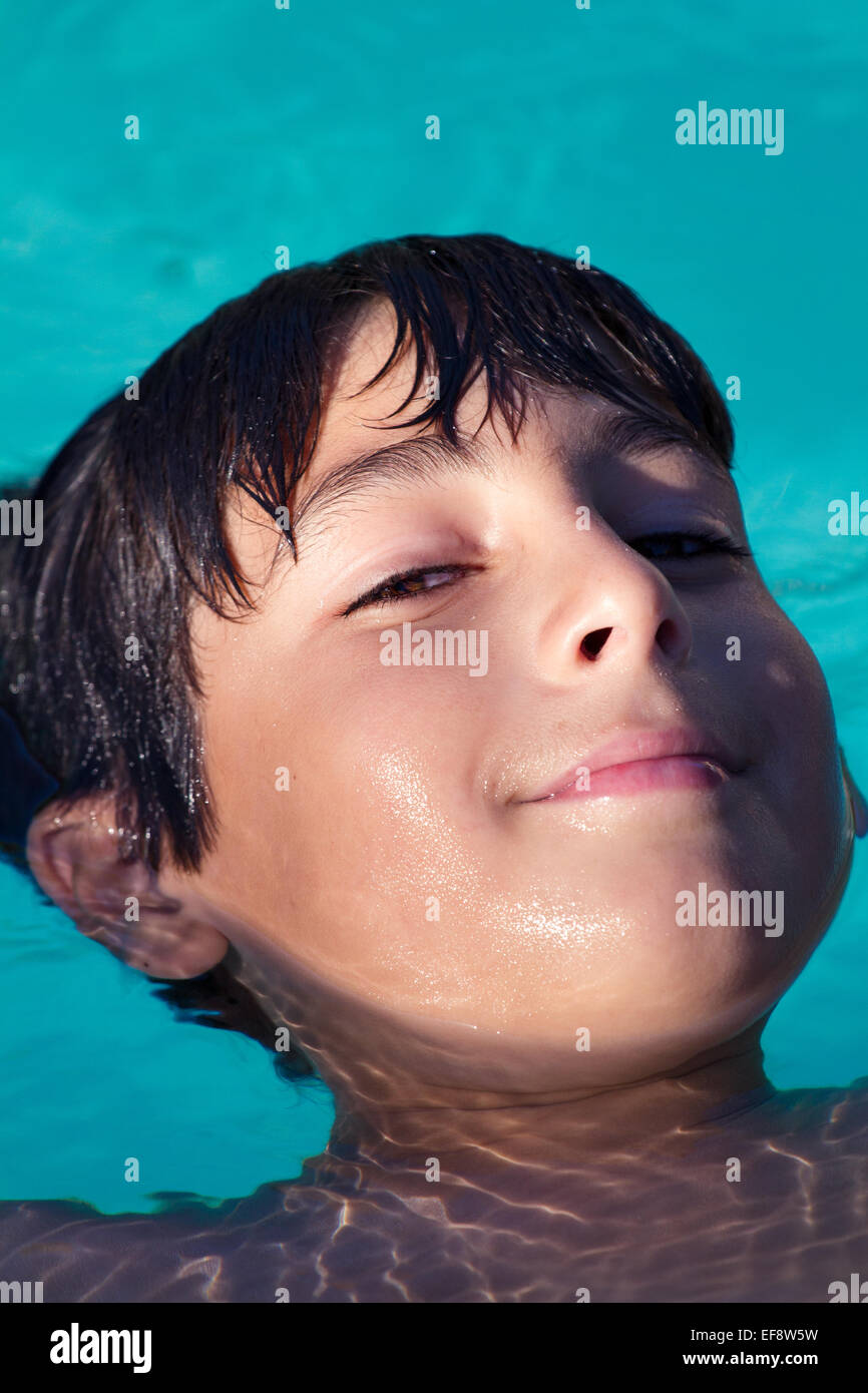 Primer plano de un niño sonriente flotando en la espalda en una piscina Foto de stock