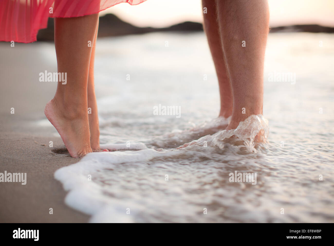 Primer plano de un par de pie tobillo en las profundidades del agua en la playa Foto de stock