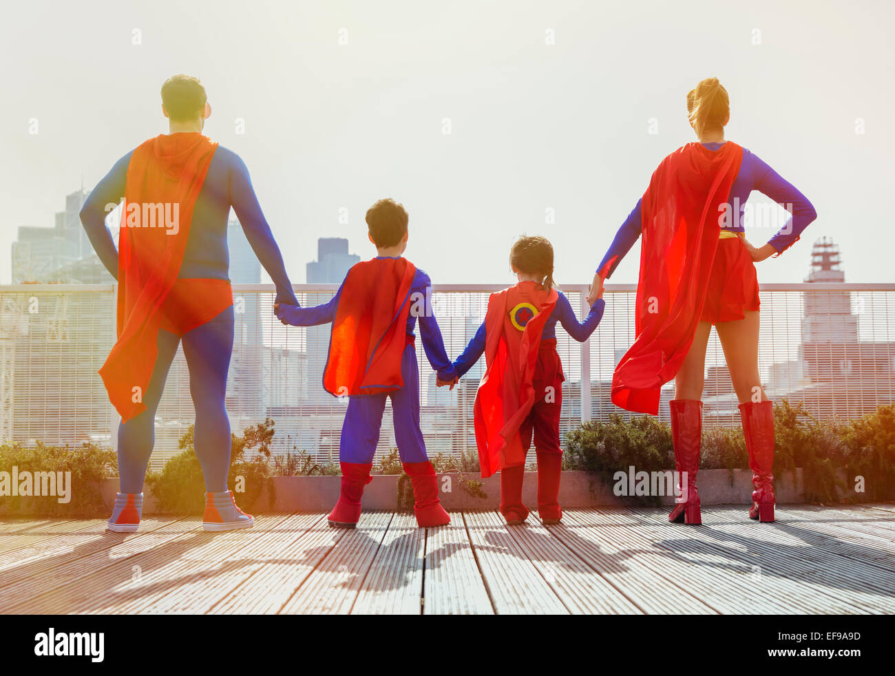 La familia de superhéroes de pie en la azotea de la ciudad Foto de stock