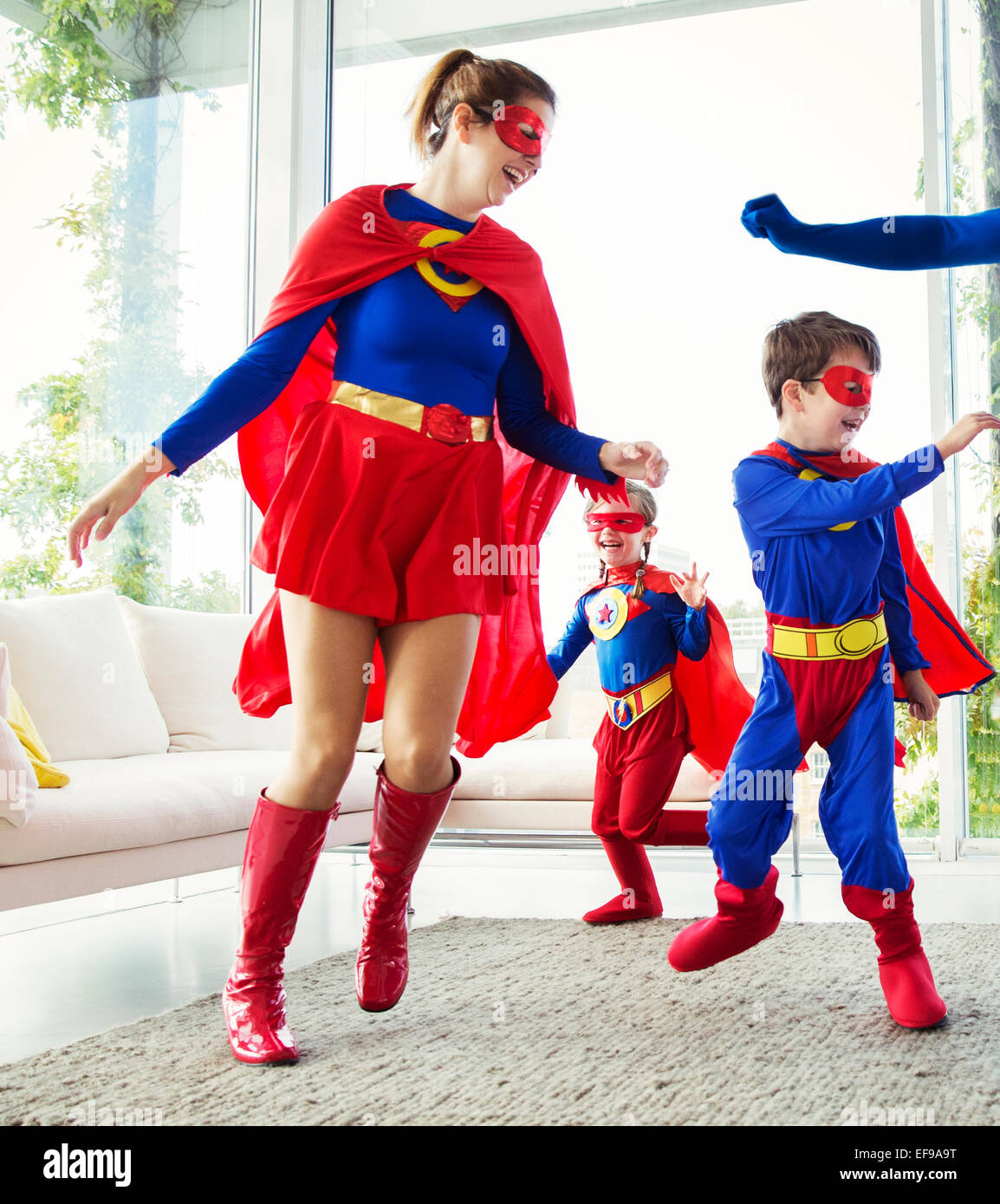 Familia de superhéroes jugando en el salón Foto de stock