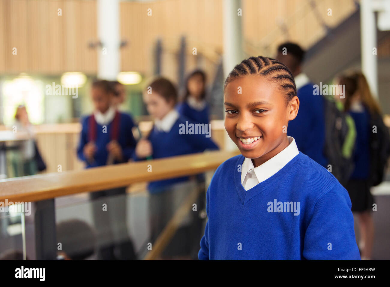 Retrato de niña de la escuela elemental sonriente vestido de azul uniforme escolar en la escuela permanente pasillo Foto de stock