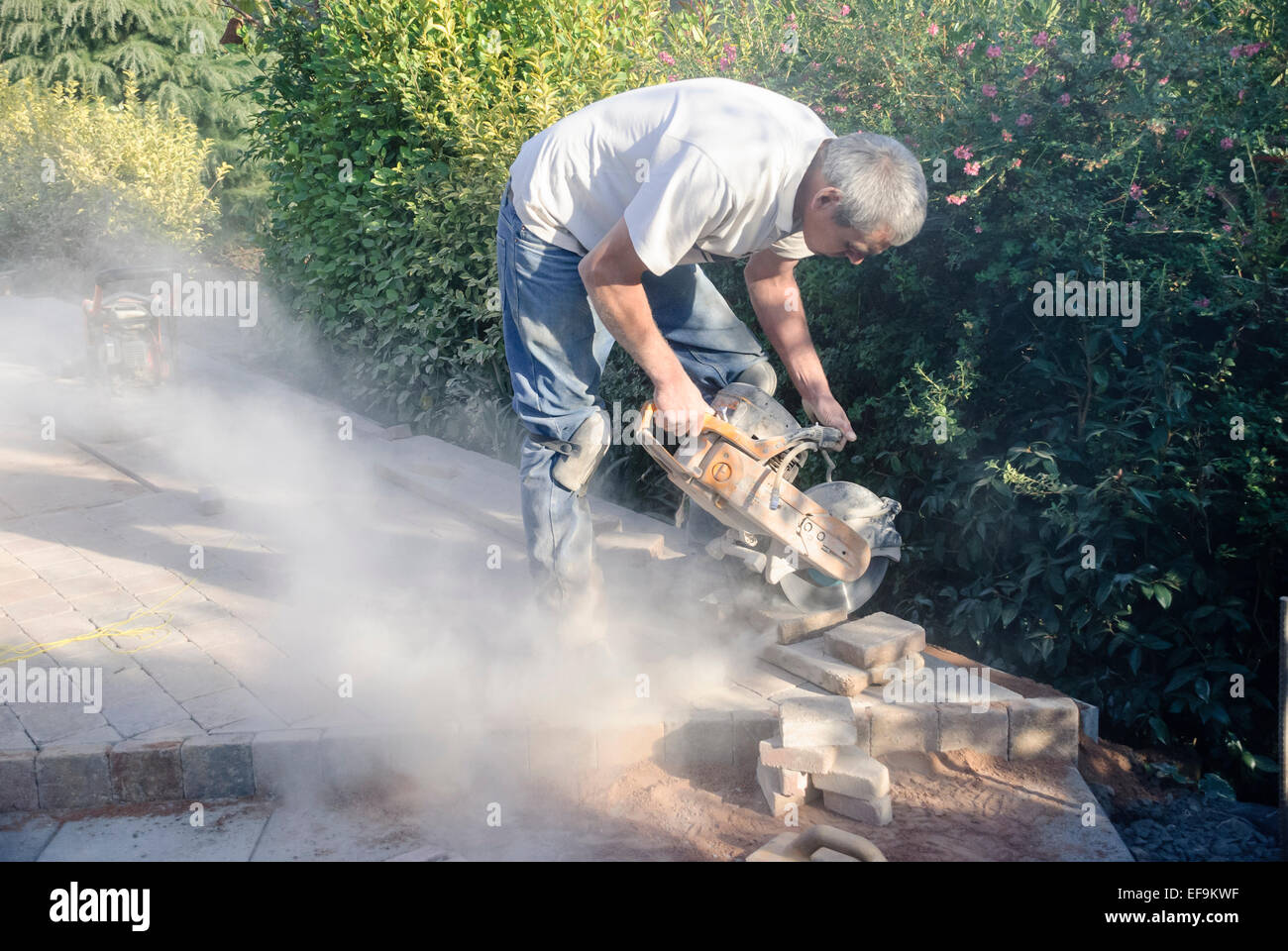 Un constructor utiliza una amoladora para cortar ladrillos mientras  establecen un patio Fotografía de stock - Alamy