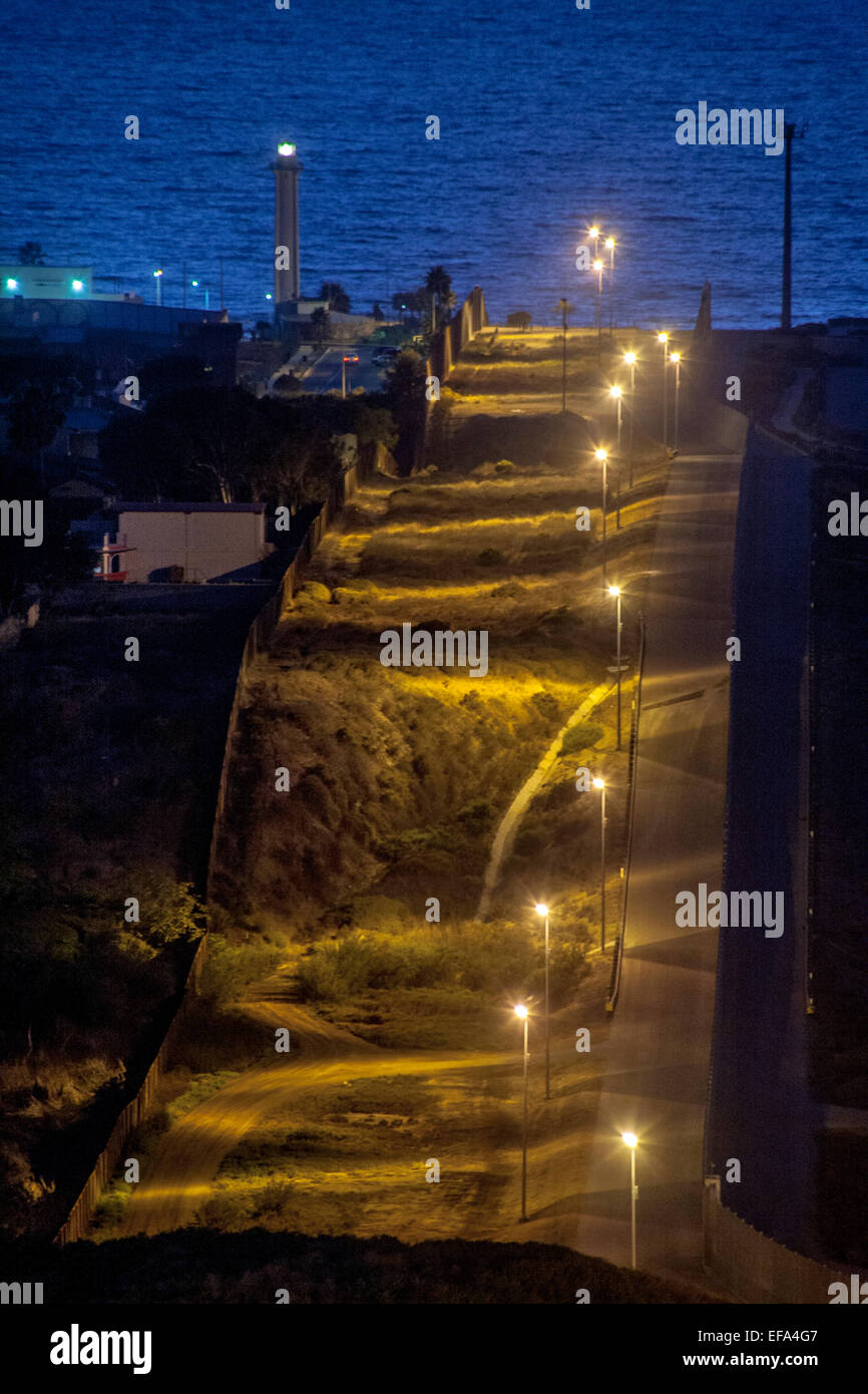 Se encienden las luces de vapor de sodio de las colinas de la frontera  internacional entre los Estados Unidos y Tijuana, México, a la izquierda.  Nota del Océano Pacífico y el faro