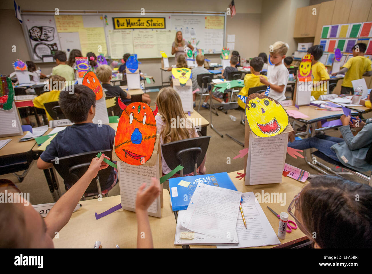Los estudiantes multirracial en Irvine, CA, escuela primaria writing class son estimulados a crear obras de arte de recorte monstruos para utilizar como temas específicos. Nota firmar en segundo plano. Foto de stock