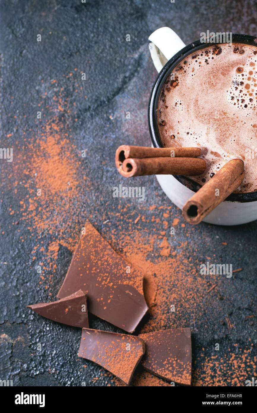 Añada la taza de chocolate caliente con palitos de canela sobre fondo oscuro. Vista desde arriba. Foto de stock