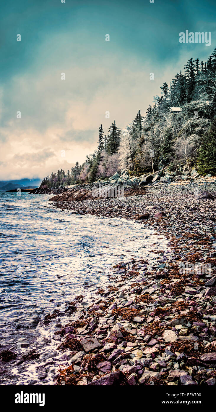 Cabaña en un acantilado junto al mar con nubes de tormenta procesado con coloración de un aspecto artístico. Foto de stock