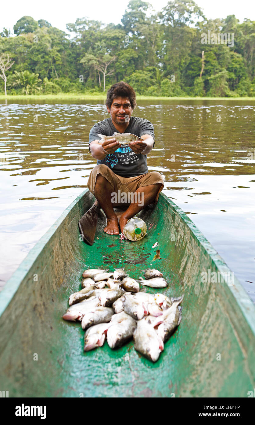 El pescador, de 28 años, sentada en una piragua y sosteniendo un Roncador o tambor de agua dulce en sus manos, la Laguna Penitencia Foto de stock