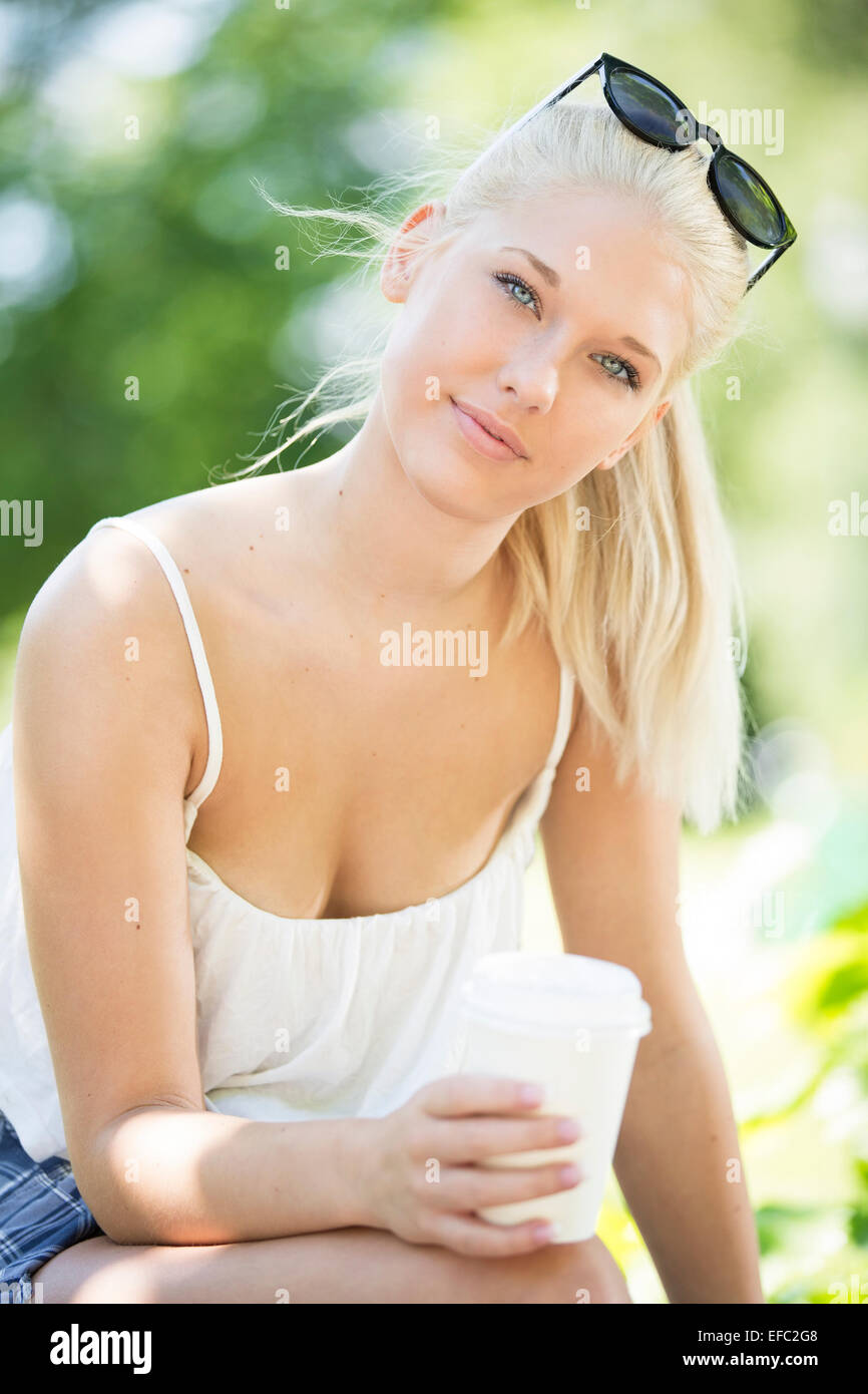 Atractiva joven bebiendo café en el parque Foto de stock