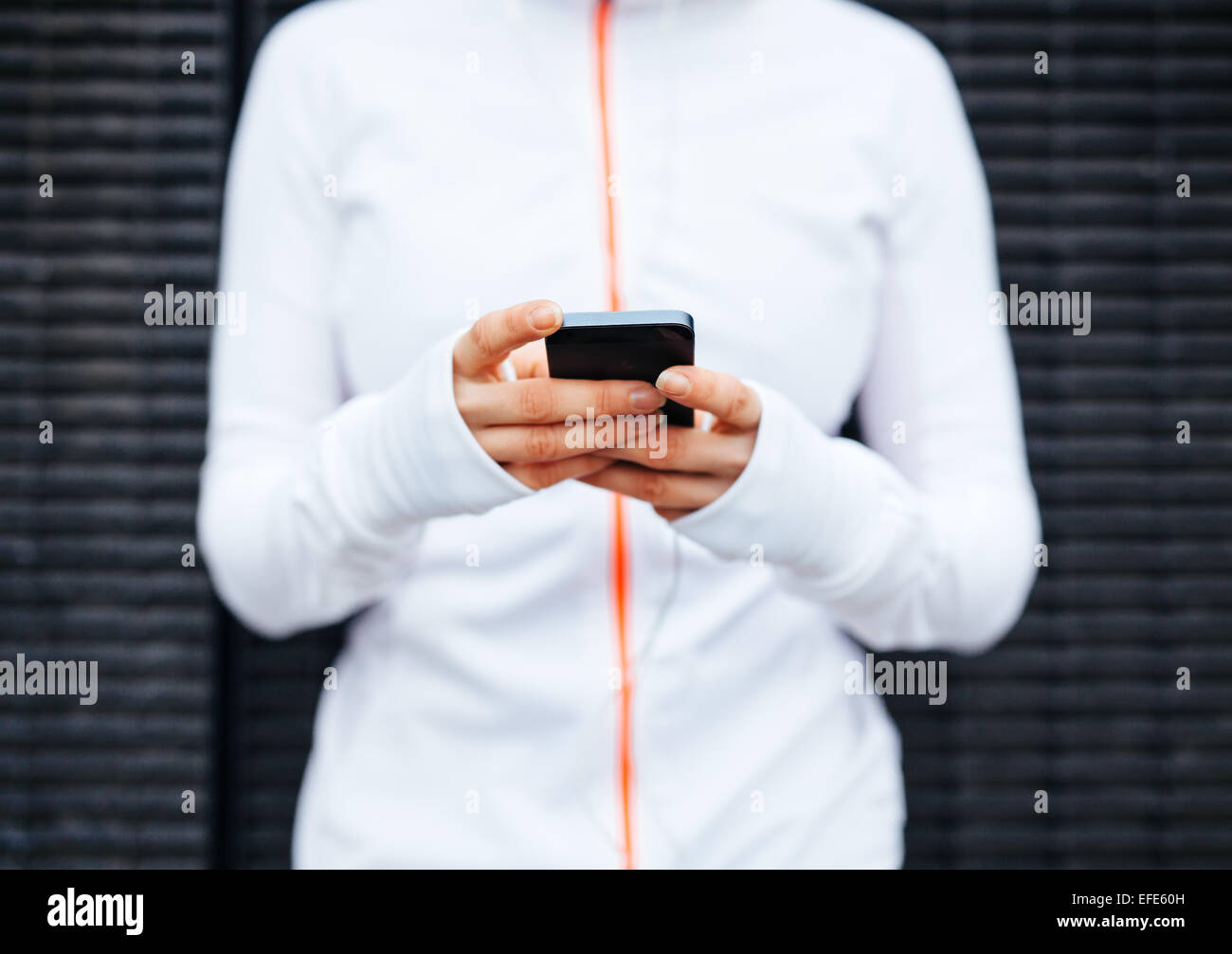 Primer plano de una mujer joven tomando un descanso forma entrenar a través de teléfono móvil. Se centran en las manos y el teléfono inteligente. Foto de stock