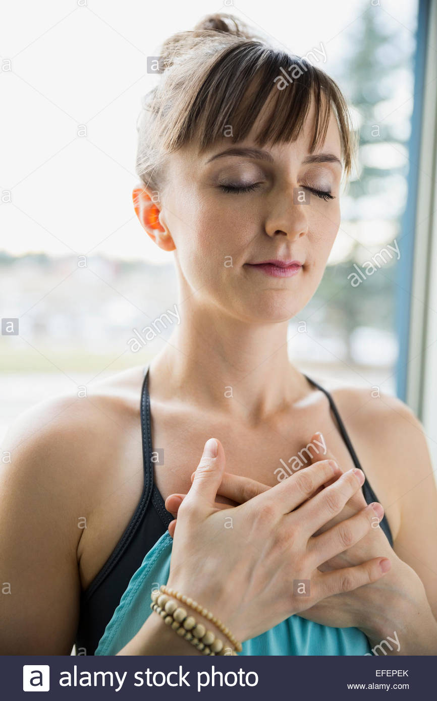 Mujer meditando con las manos sobre el corazón Foto de stock
