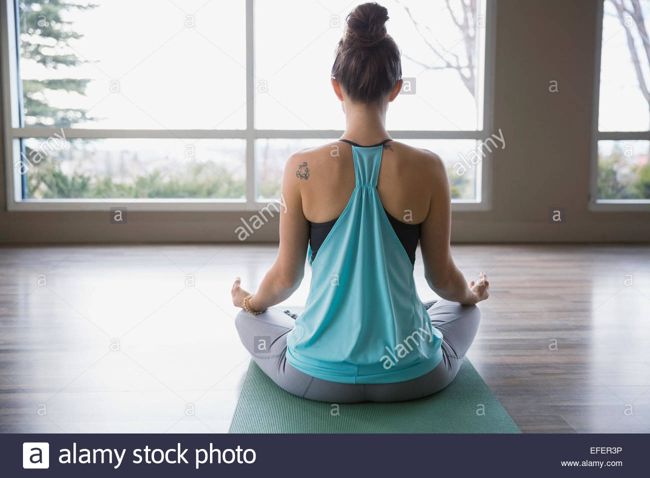 Vista trasera de la mujer meditando en posición de loto Foto de stock