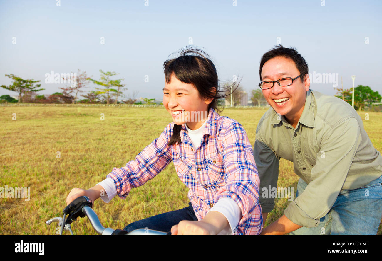 Padre feliz enseñando hijo a andar en bicicleta Foto de stock