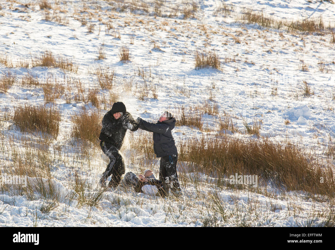 Los niños tienen una lucha de bolas de nieve sobre Kirkstone Pass en nieve, Lake District, RU Foto de stock