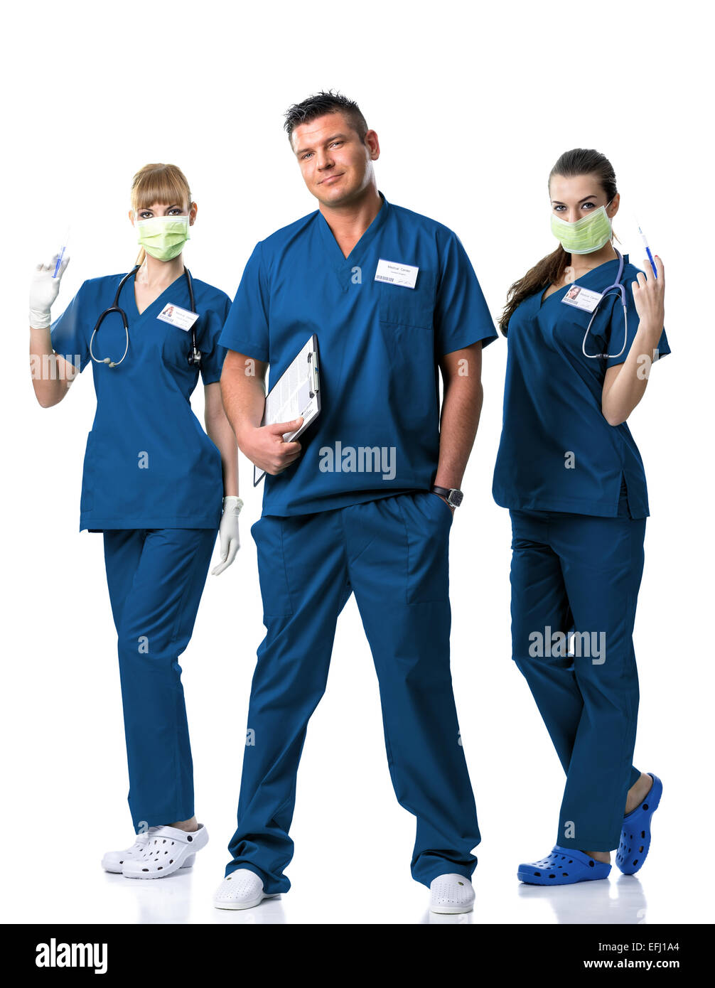 Equipo de cirugía -médico, dos enfermeros en vestido azul, en la mascarilla de boca, con inyecciones y el estetoscopio Foto de stock