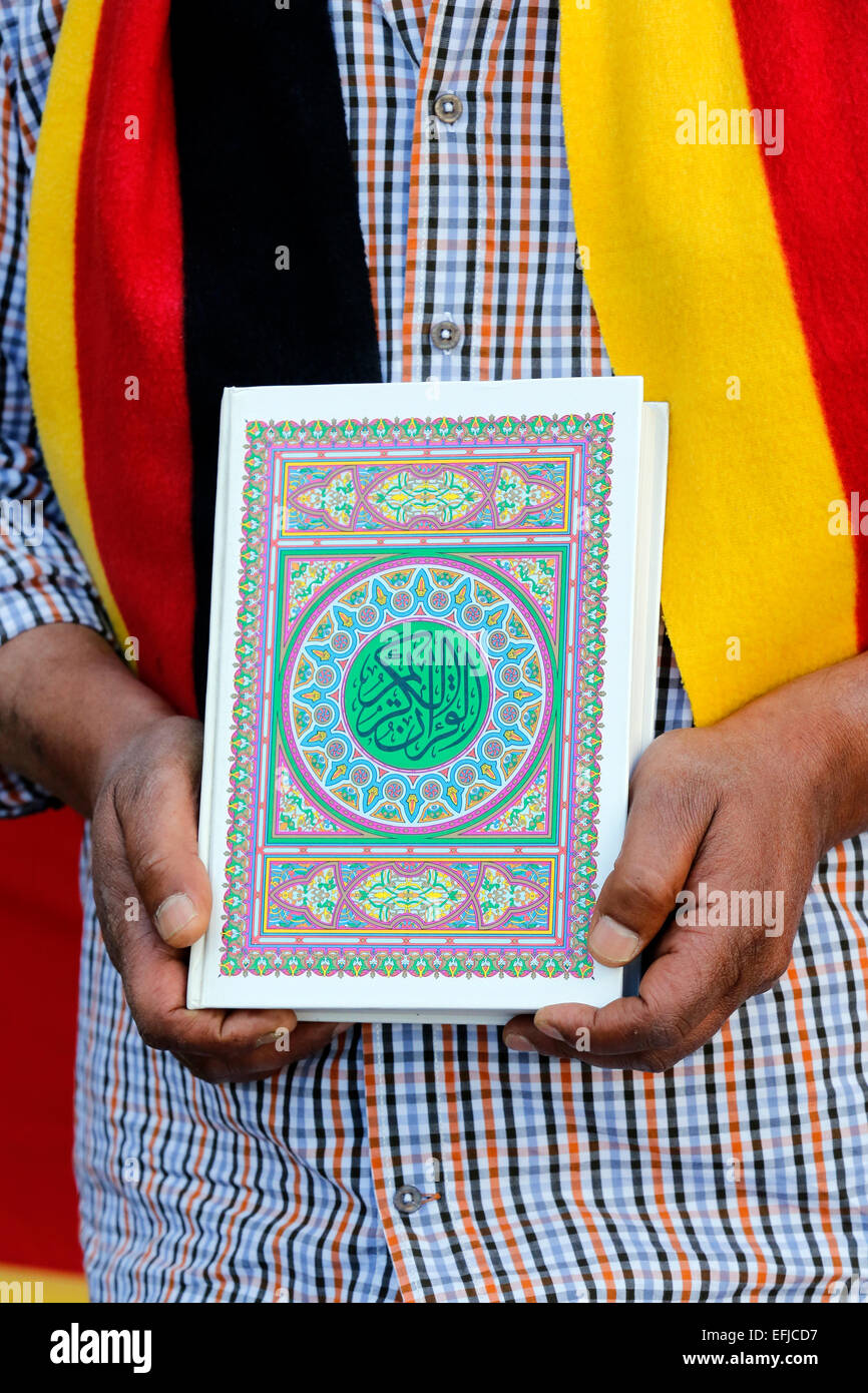 Turco hombre vestido con bufanda en alemán banderas de colores (negro oro  rojo) mantiene el Corán, el libro sagrado de los musulmanes en sus manos.  Dortmund/Alemania Fotografía de stock - Alamy