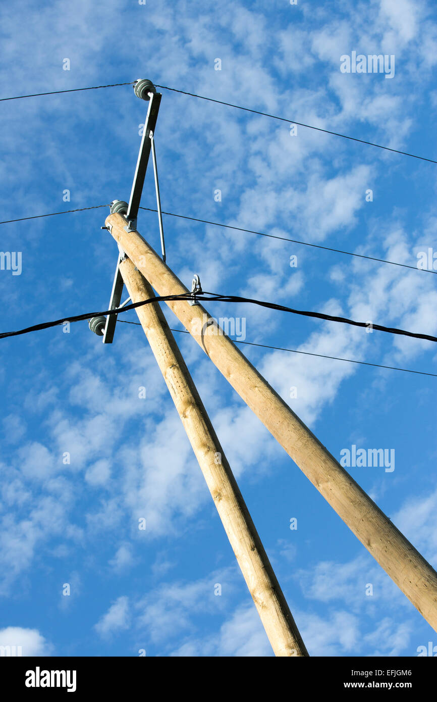 Nuevo polo de madera con cables de línea de alimentación, brazo transversal y aislantes contra el cielo azul Foto de stock