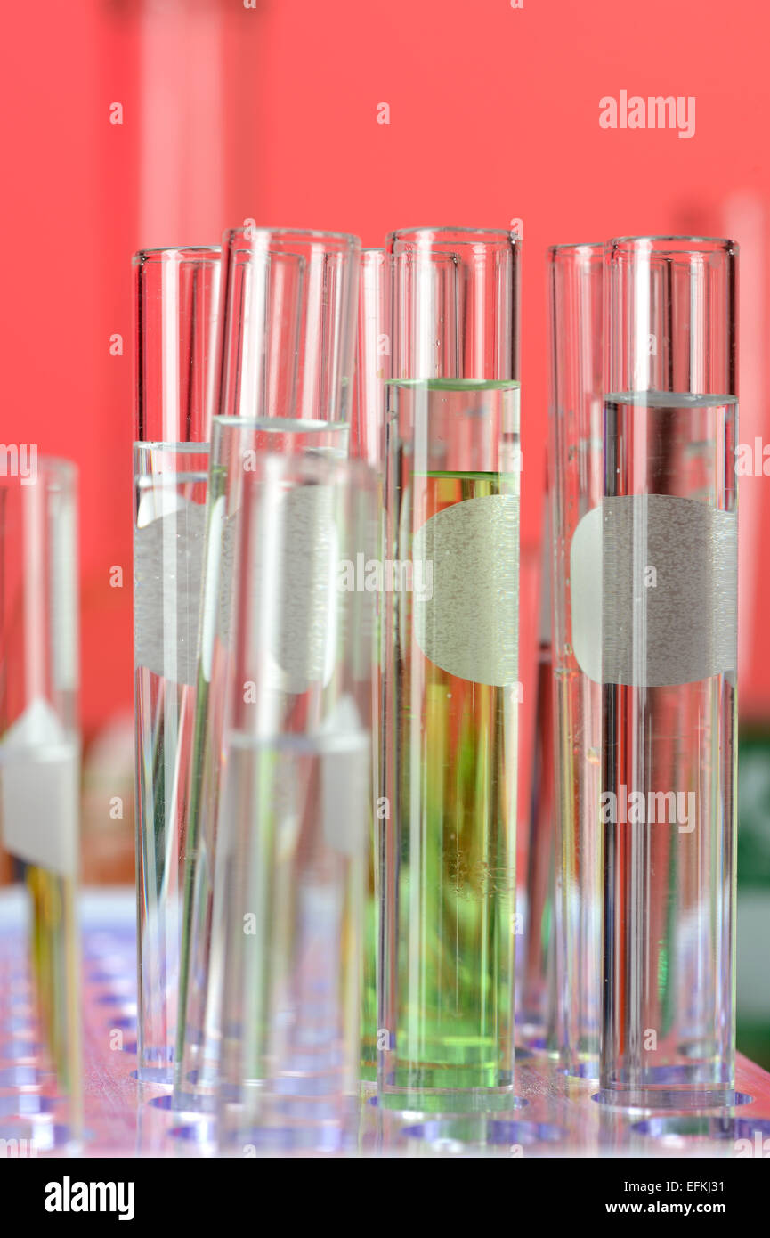 Tubos de ensayo de laboratorio en el stand sobre fondo rojo. Foto de stock