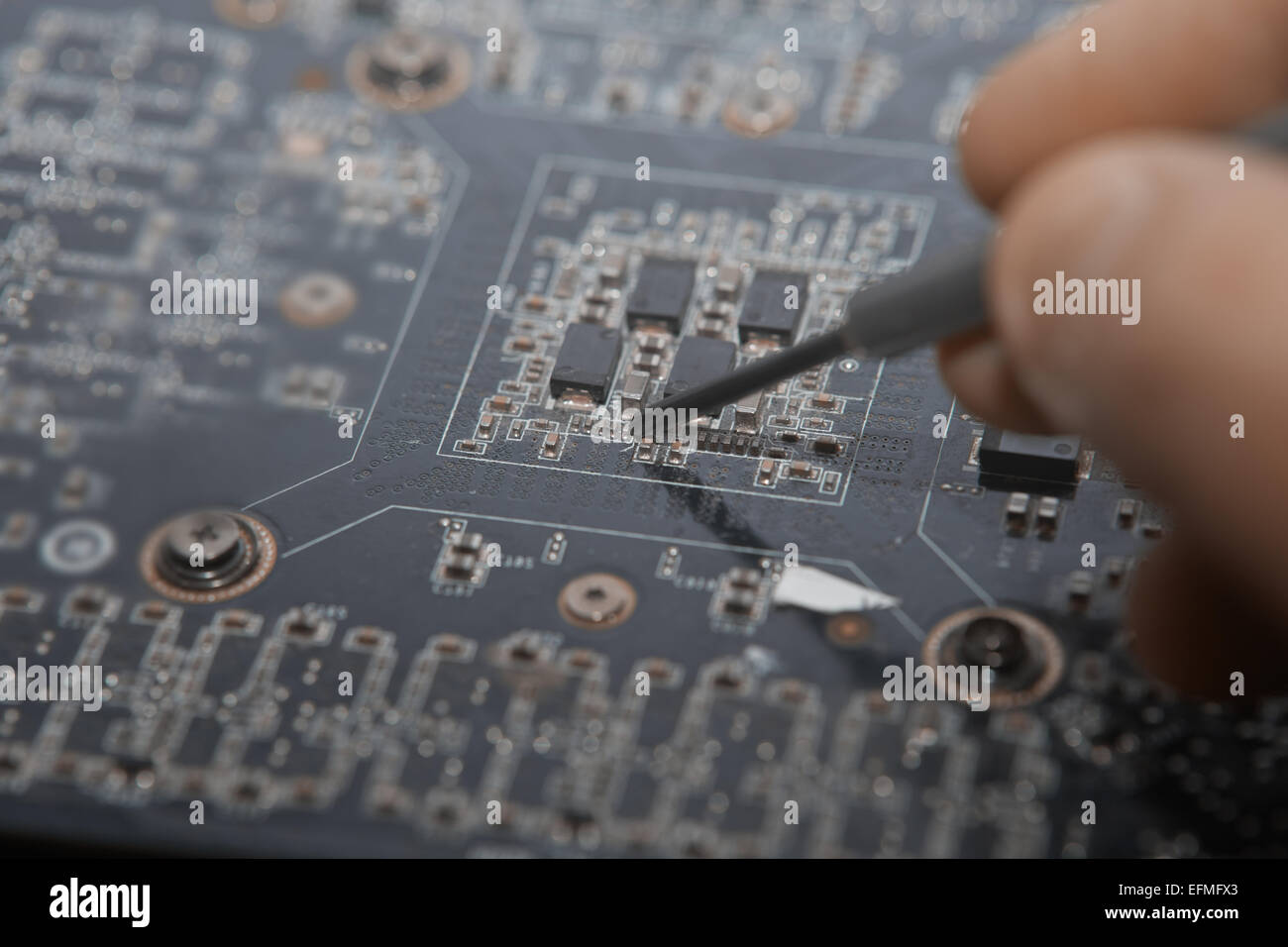 Los dedos humanos hacer la reparación de motherboard. La foto Foto de stock