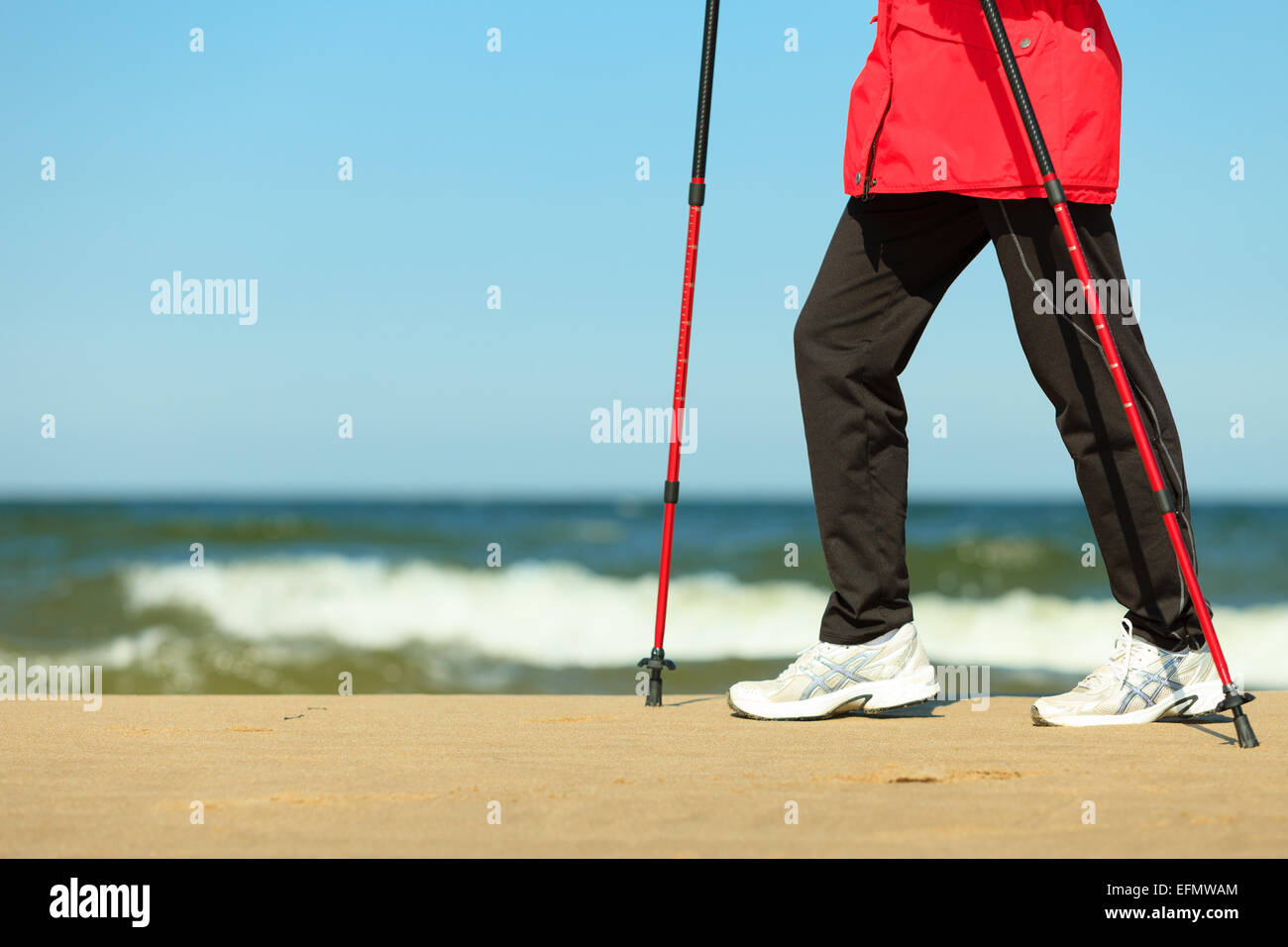 Nordic Walking. Primer plano de piernas femeninas caminatas en la playa