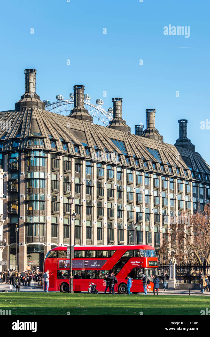 Un autobús rojo de Londres es visto a través de la Plaza del Parlamento, detrás de la cual se Portcullis House y el Ojo de Londres Foto de stock