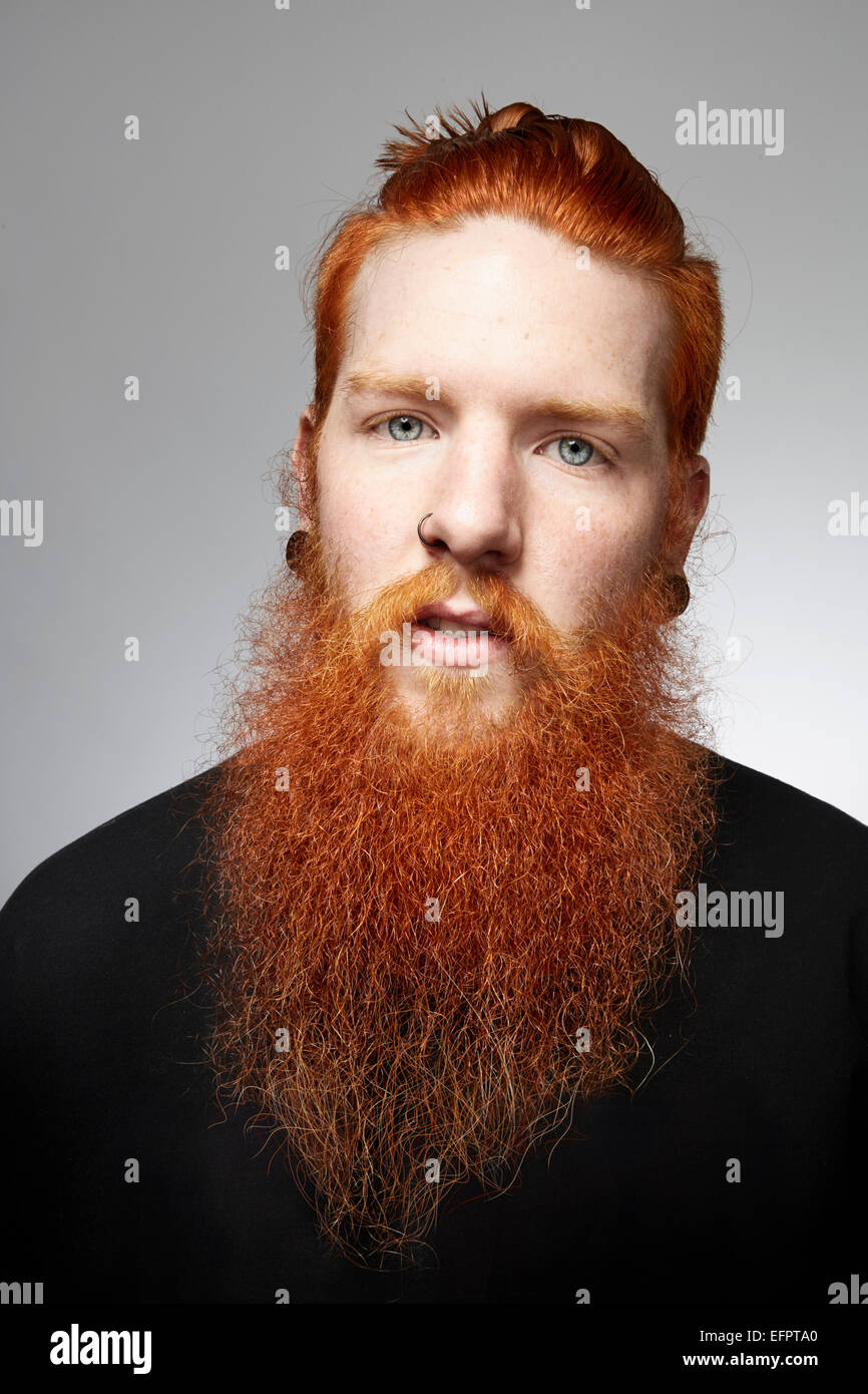 Retrato de estudio de staring joven con barba y cubierto de pelo rojo Foto de stock