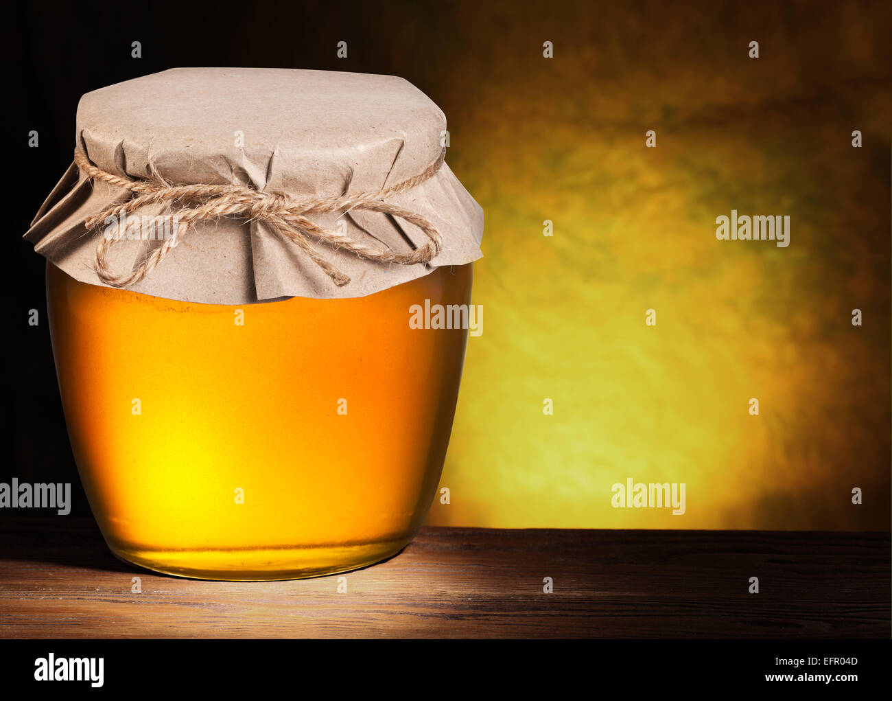 Vaso lleno de miel sobre fondo marrón. Foto de stock