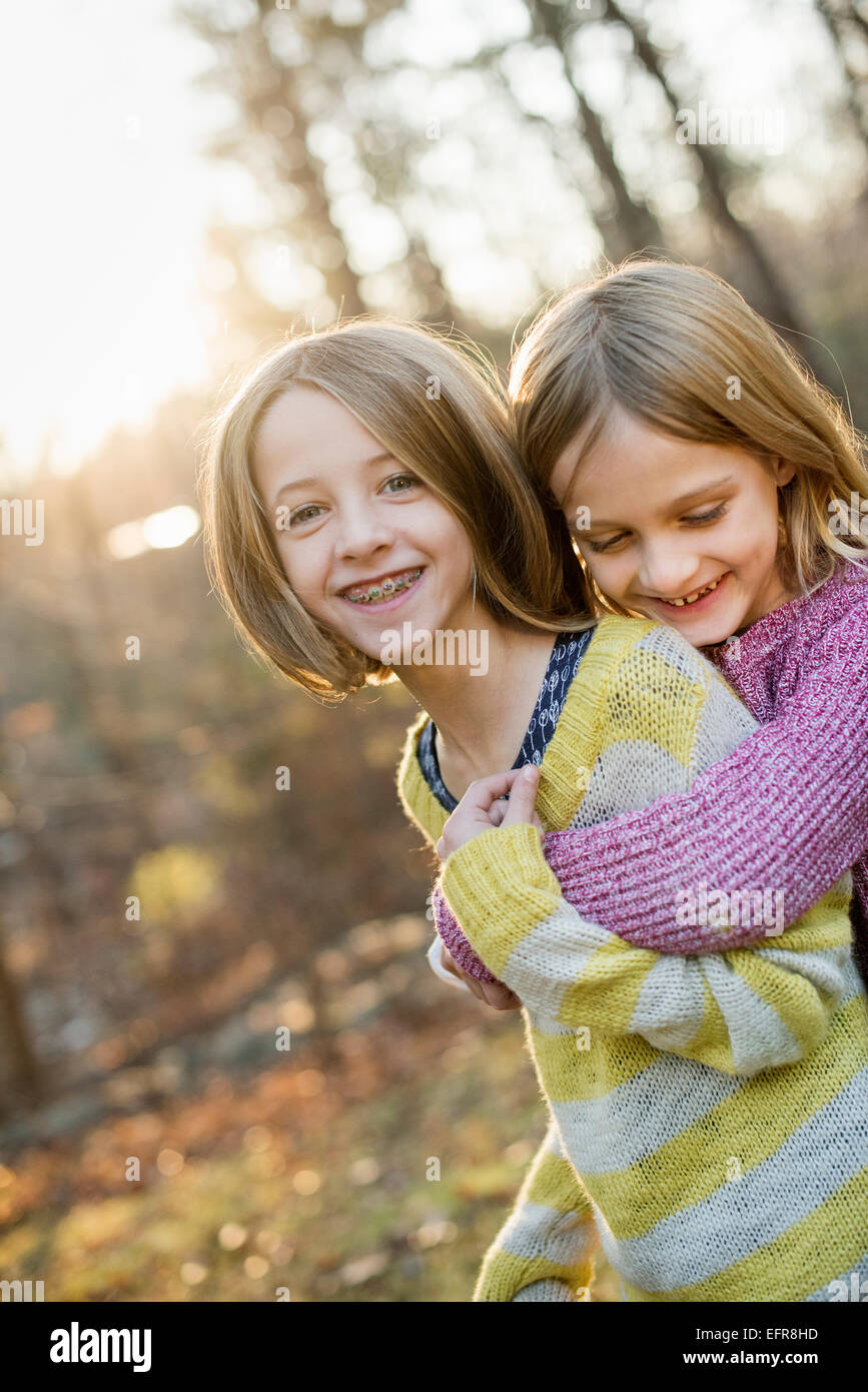 Dos niñas sonrientes en un bosque, abrazarse mutuamente. Foto de stock