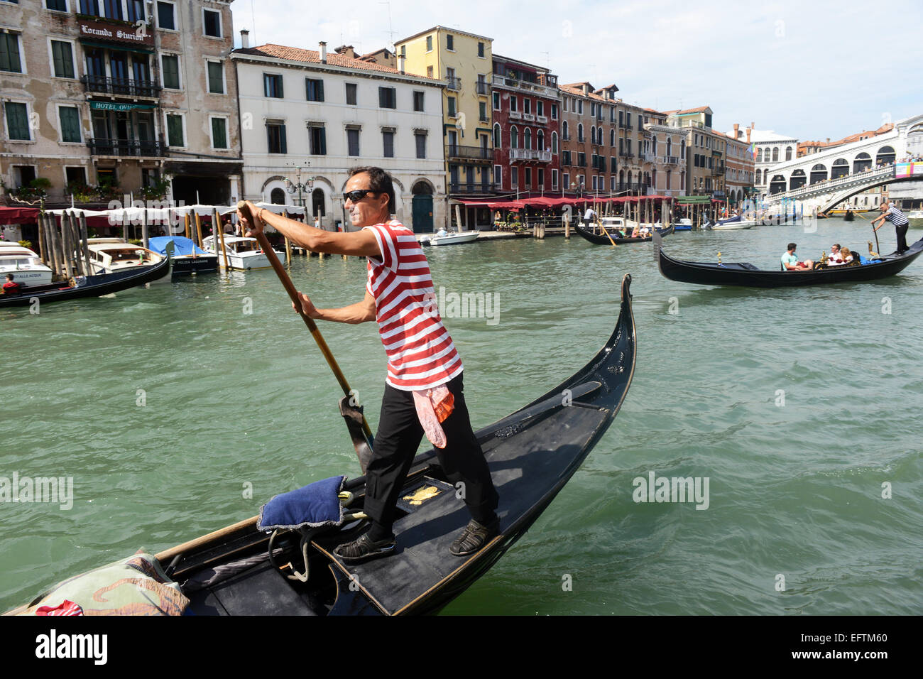 Gondolero dirige su góndola hacia arriba y hacia abajo el Gran Canal de Venecia, Italia. Foto de stock