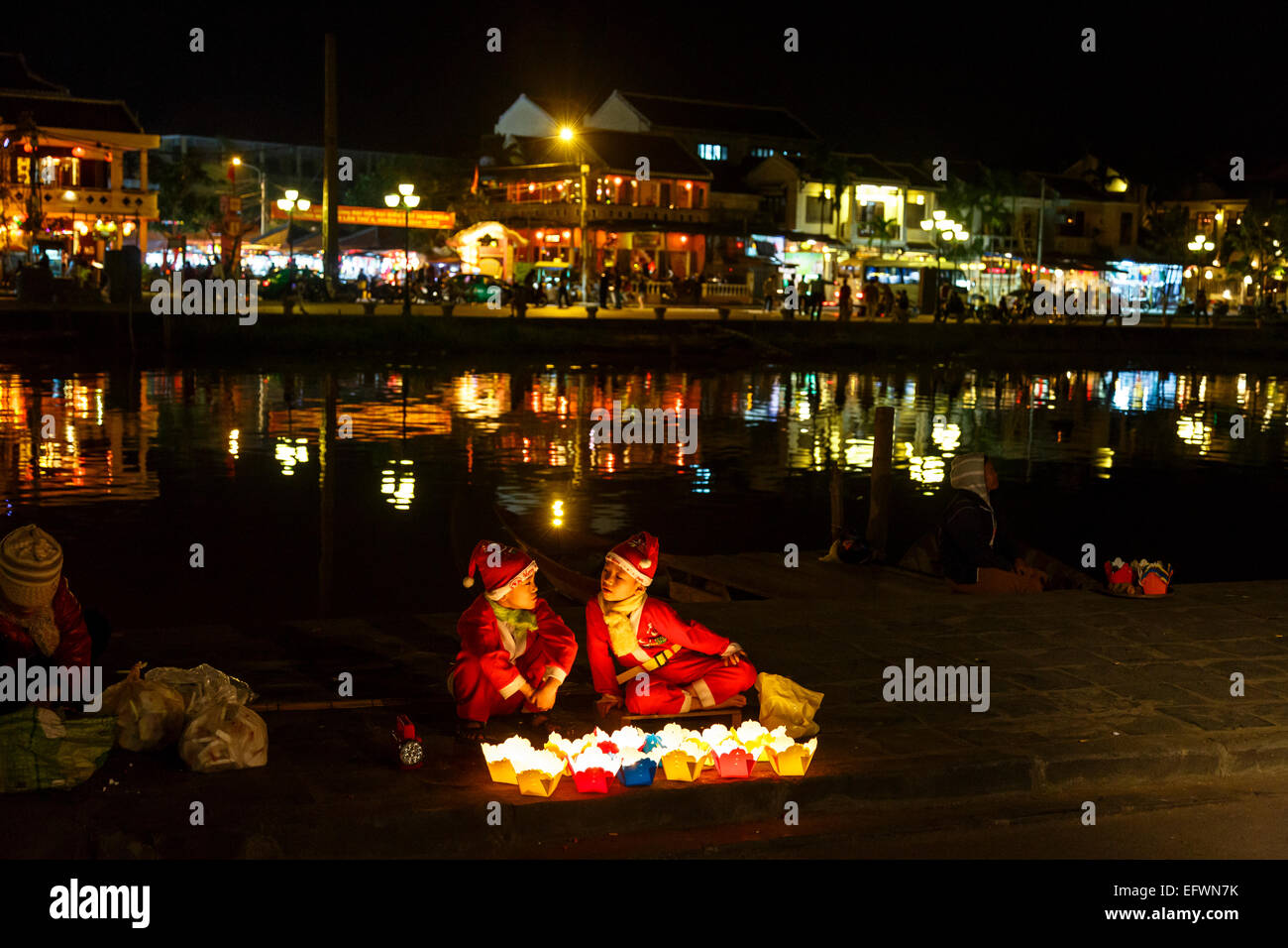 Niños vestidos como Santa Claus vendiendo velas flotantes, Hoi An, Vietnam. Foto de stock