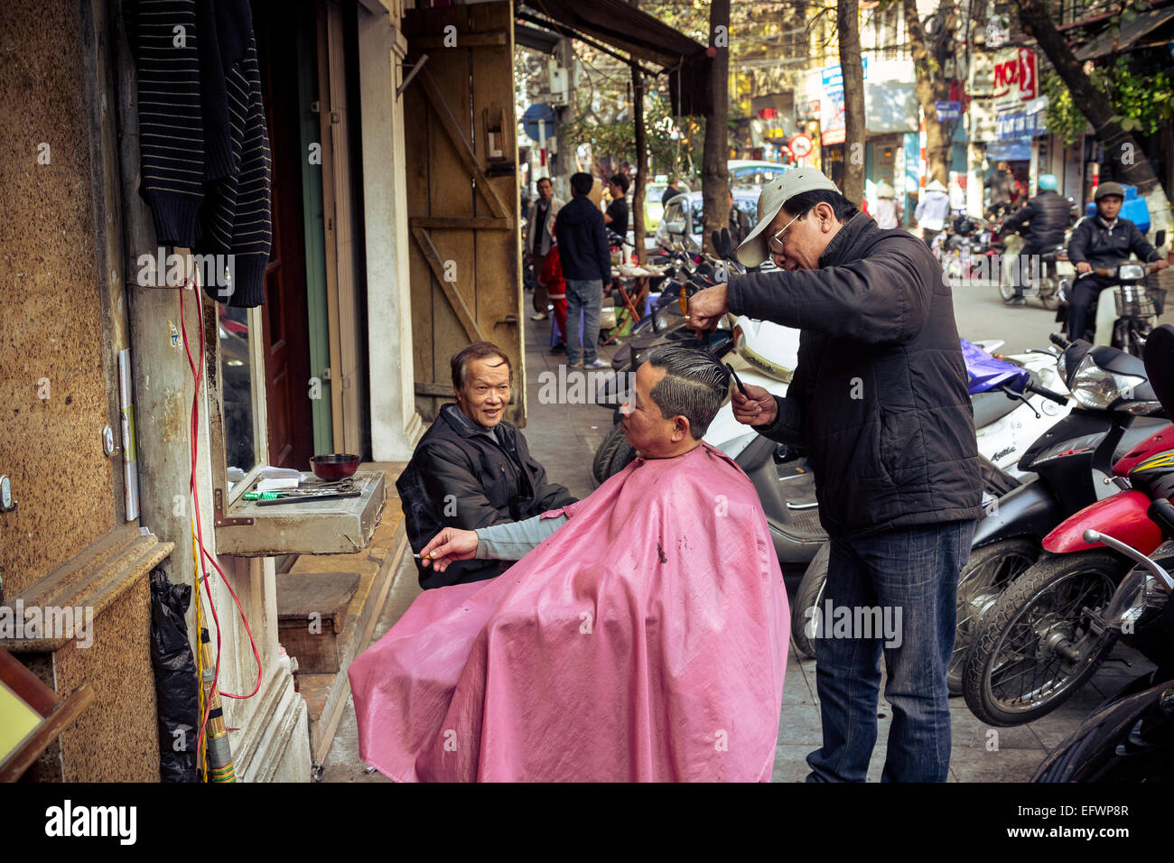 Barbero en la calle en el barrio antiguo de Hanoi, Vietnam. Foto de stock