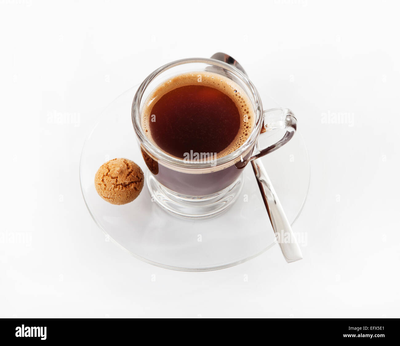 Taza de café de vidrio con una cuchara y galleta sobre un fondo blanco. Foto de stock