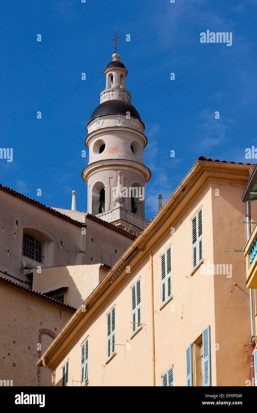 Torre de la iglesia de St Michel Menton con color durazno casa con persianas lblue en primer plano Alpes-Maritimes Cote d'Azur, Francia Foto de stock