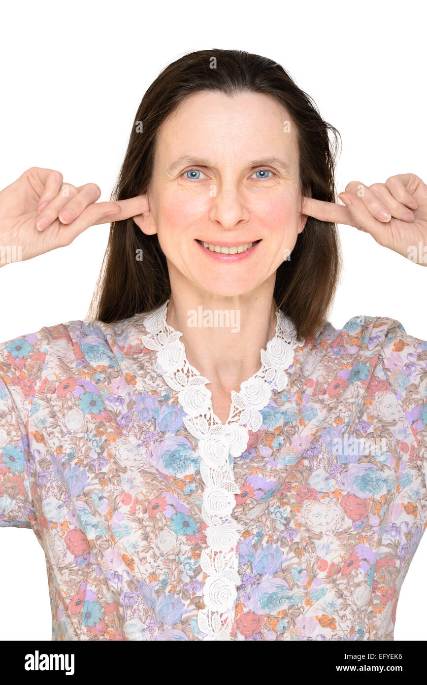 Sonriente mujer adulta manteniendo cerradas las orejas con sus dedos, en el sentido de que ella no quiere oír nada o ella es sorda Foto de stock