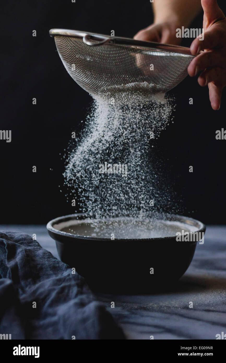 Tamizar la harina en un tazón mientras cocinar Foto de stock