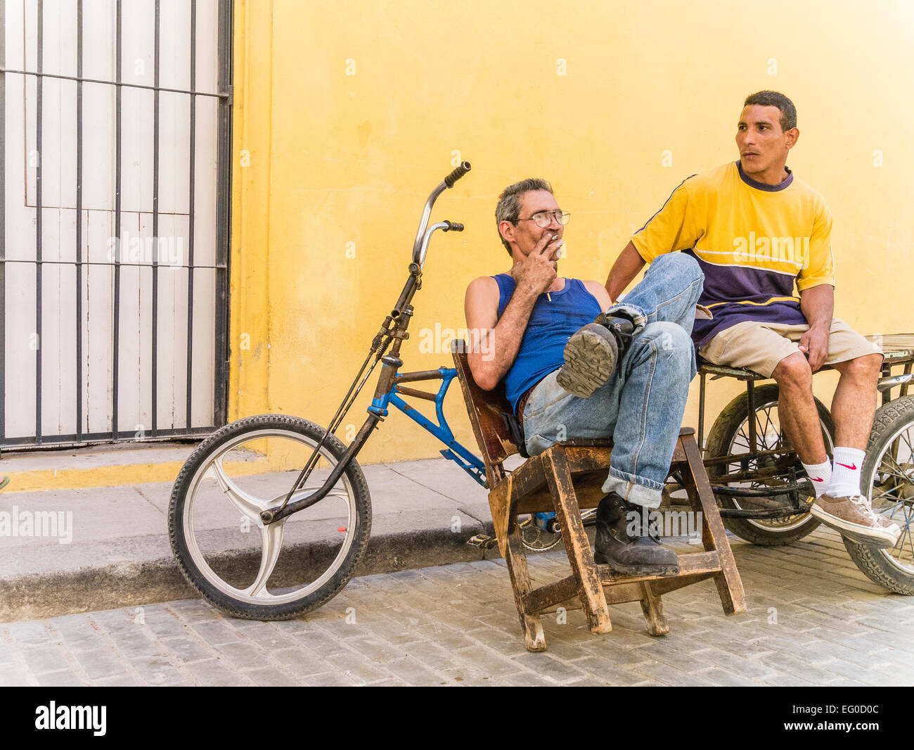 https://c8.alamy.com/compes/eg0d0c/dos-hombres-se-sientan-entrega-de-bicicletas-por-su-entrega-3-ruedas-bicicletas-contra-una-pared-amarilla-y-hablar-en-la-habana-vieja-cuba-eg0d0c.jpg