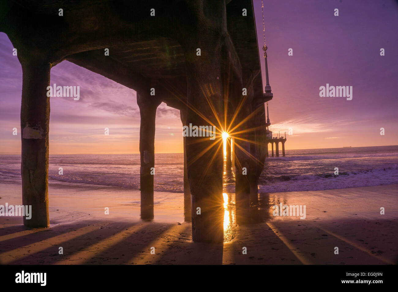 California, Estados Unidos, Manhattan Beach, Sunbeam viene a través de la construcción de pilas, cielo púrpura Foto de stock