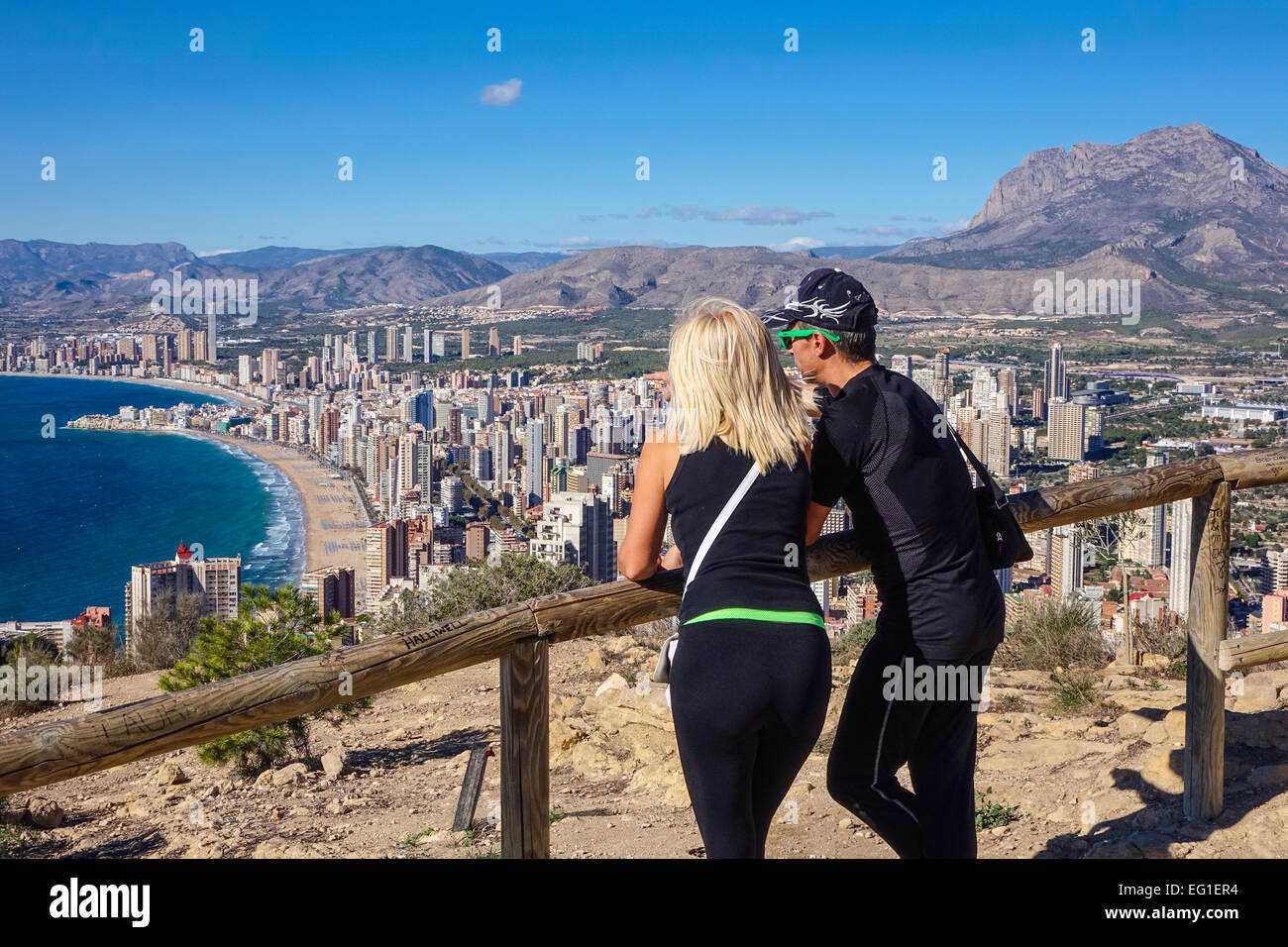 Los turistas vistiendo ropa deportiva admirando las vistas de Benidorm, Costa Blanca, España. Tomada cerca detrás de ellos. Foto de stock