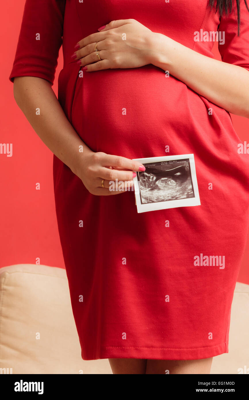 Nuevo concepto de vida. El embarazo, la maternidad y la felicidad. Closeup  barriga de embarazada luciendo un elegante vestido rojo, ultrasonido sca  Fotografía de stock - Alamy