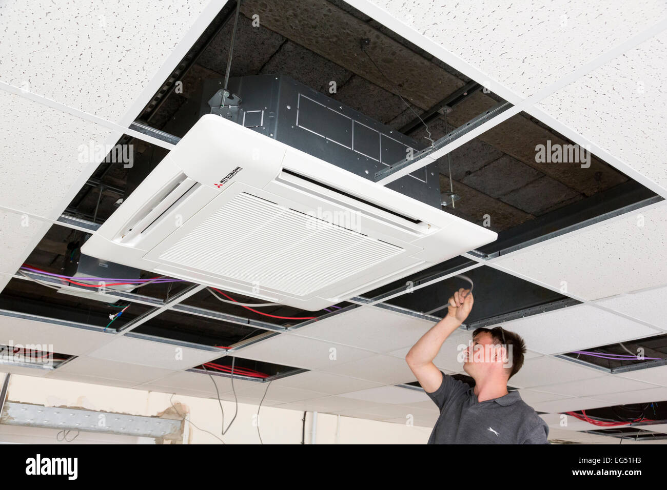 Instalación de la unidad de aire acondicionado electricista suspendidas en el techo Foto de stock