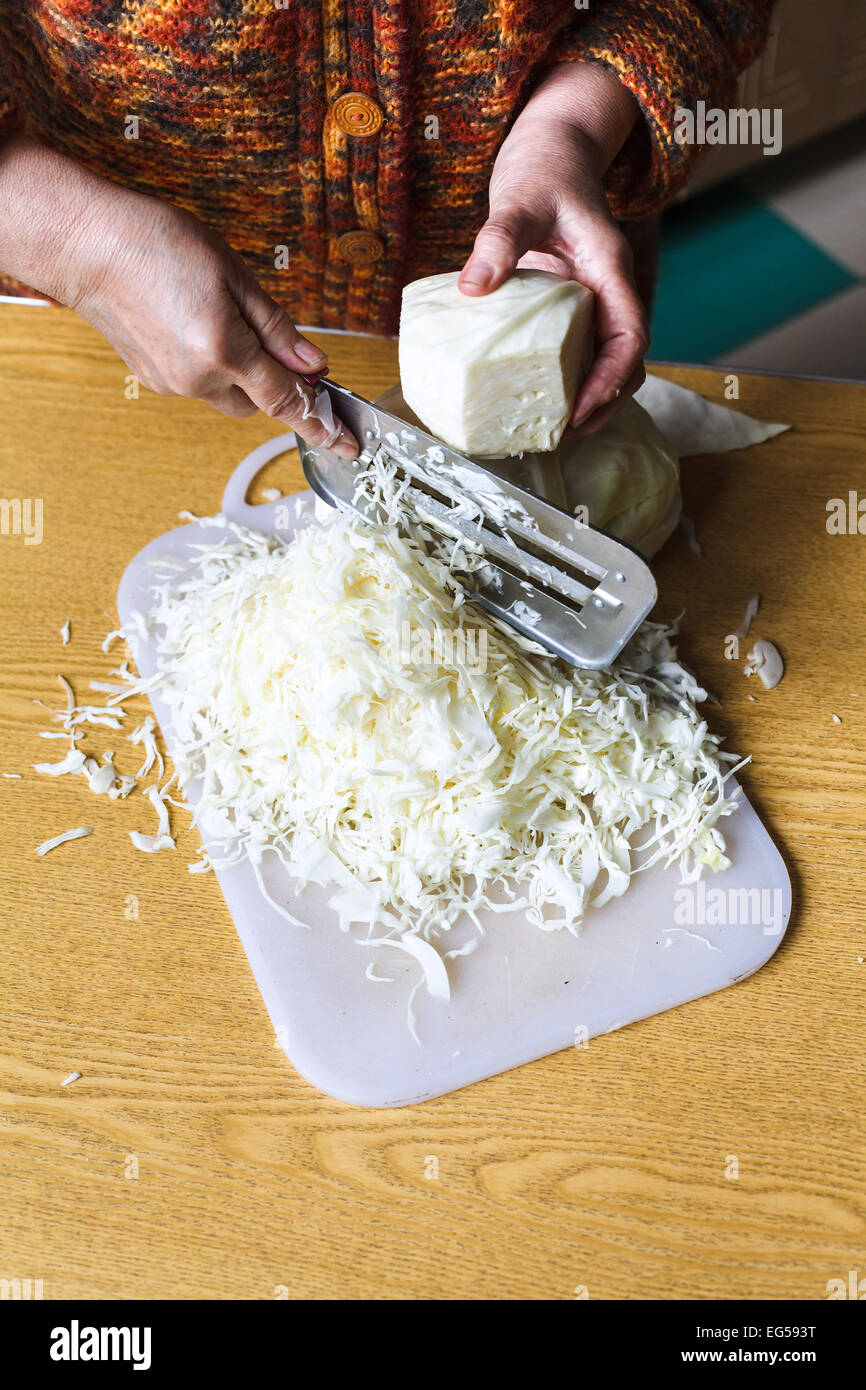 Mujer tiras de repollo ensalada de col cortador manual en la tabla