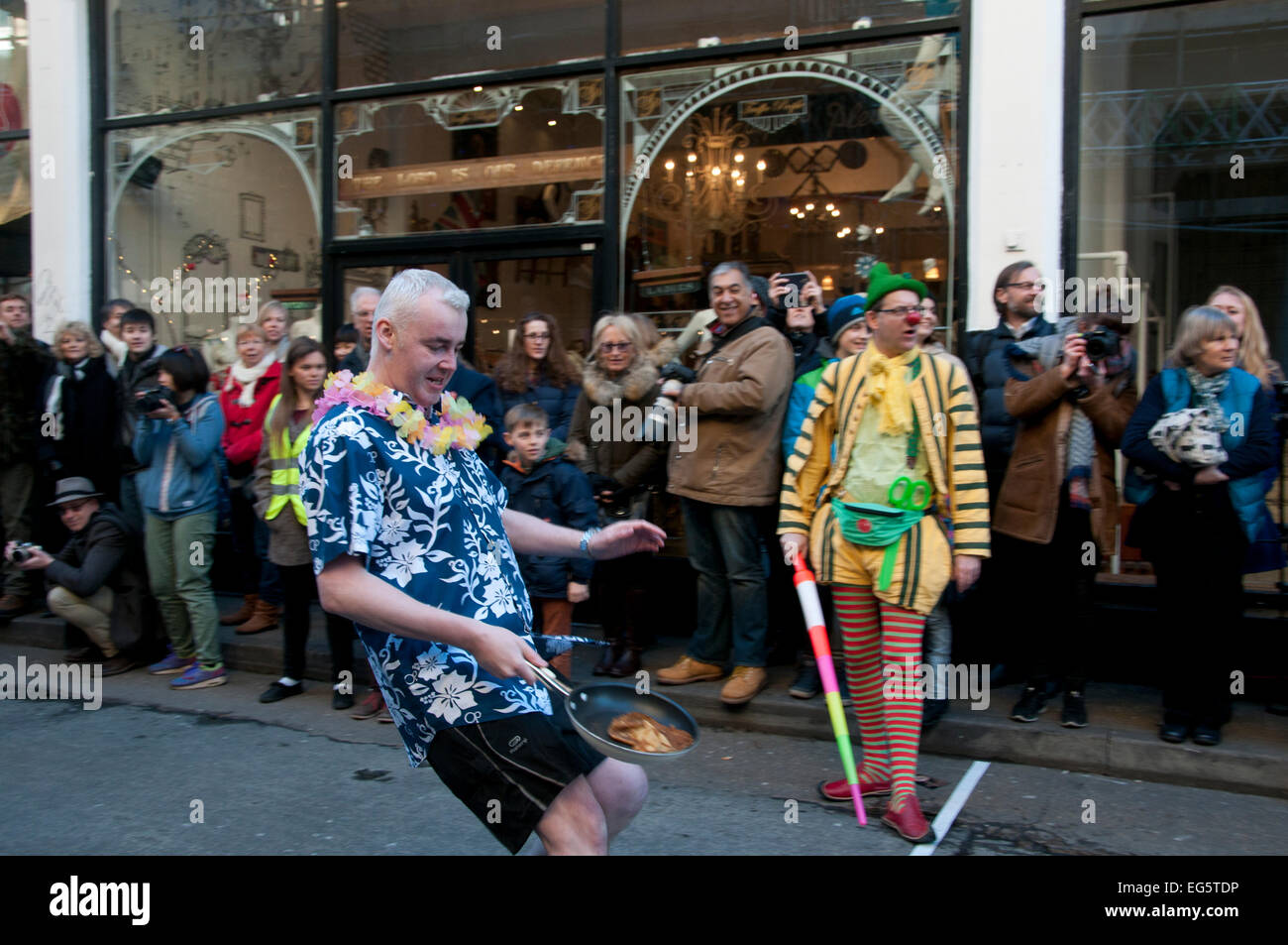 El Martes de Carnaval pancake race, organizada por otras artes en ayuda de London Air Ambulance competidor en la línea de acabado Foto de stock
