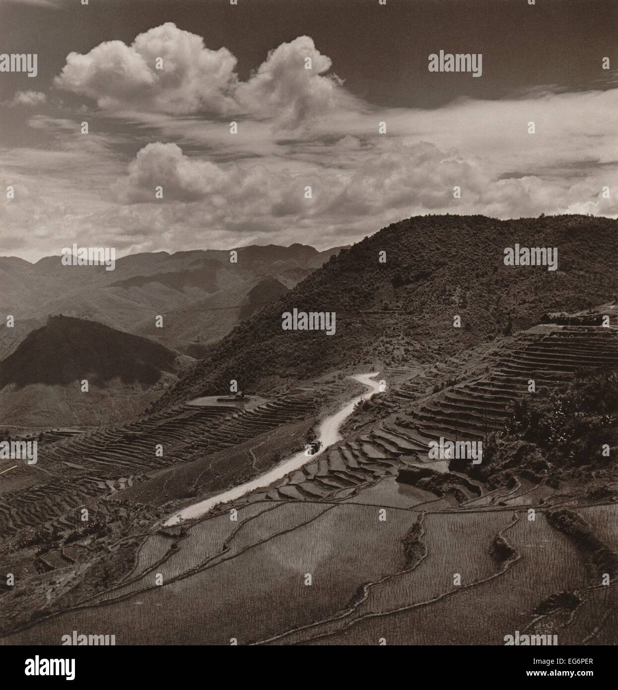 Campos de terrazas y calzada en una región montañosa de la provincia de Yunnan en China. Un vehículo militar de unidades en la distancia. Foto de stock