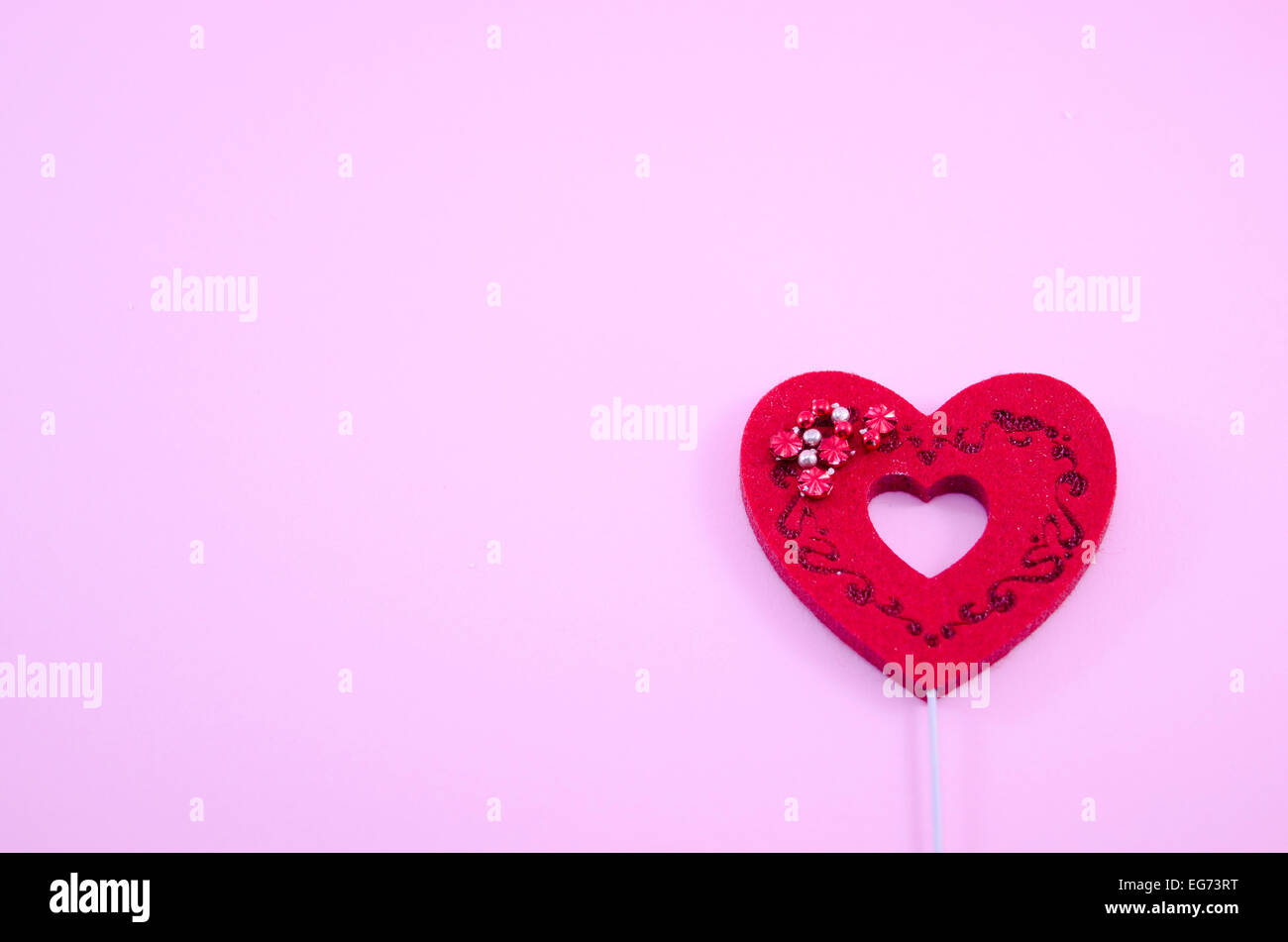 Rojo corazón grabado en papel rosa con algunas perlas brillantes Foto de stock