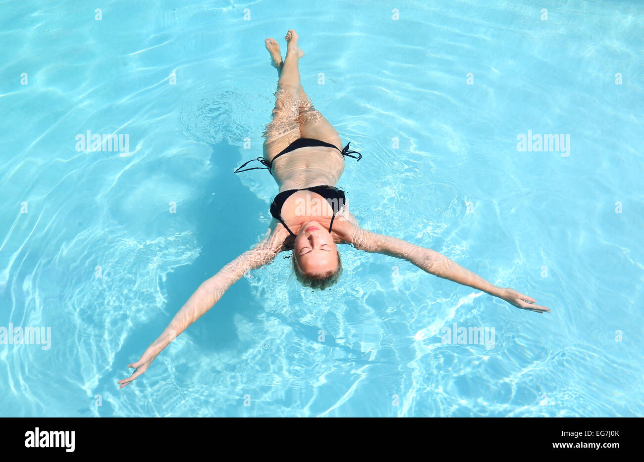 Señora caucásica flotando en la piscina. Foto de stock