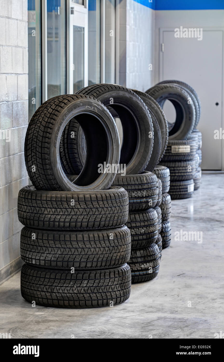 Pilas de neumáticos, con perfiles de rodadura para diversas condiciones de conducción, a la venta en un garaje de automoción Foto de stock