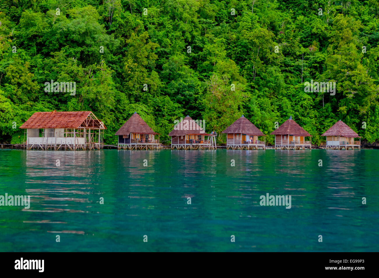 Cabañas de madera sobre el agua del mar en un fondo de bosque costero en Ora Eco-Resort en la aldea de Salman, Seram del Norte, Maluku Central, Maluku, Indonesia. Foto de stock